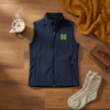 Navy soft shell vest flat lay with embroidered clover styled with casual accessories on wood surface