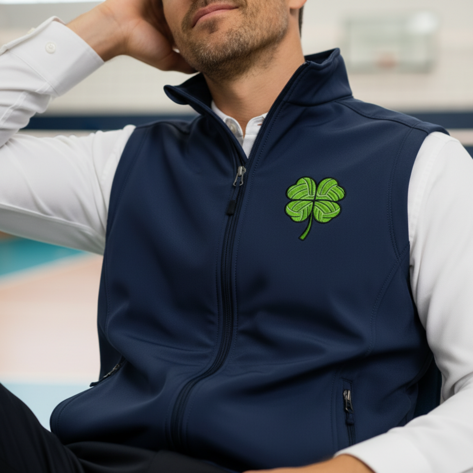 Volleyball dad wearing navy soft shell vest with green clover embroidery while standing outdoors